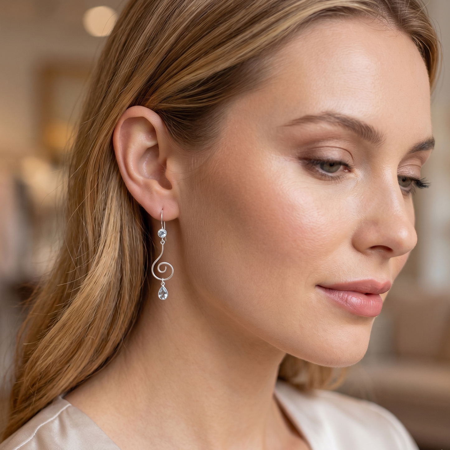 Close-up of a woman wearing elegant earrings with a blurred indoor background