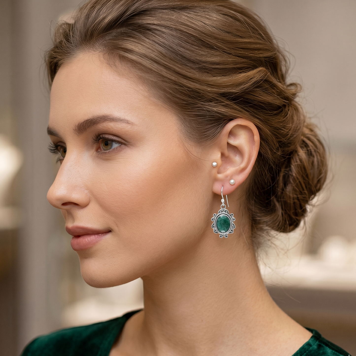 Woman wearing emerald green earrings with a blurred background