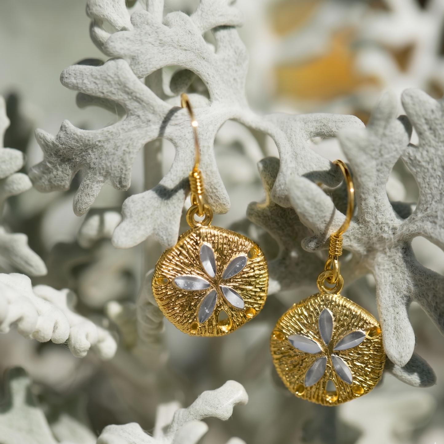 Gold earrings with floral design on a white floral background