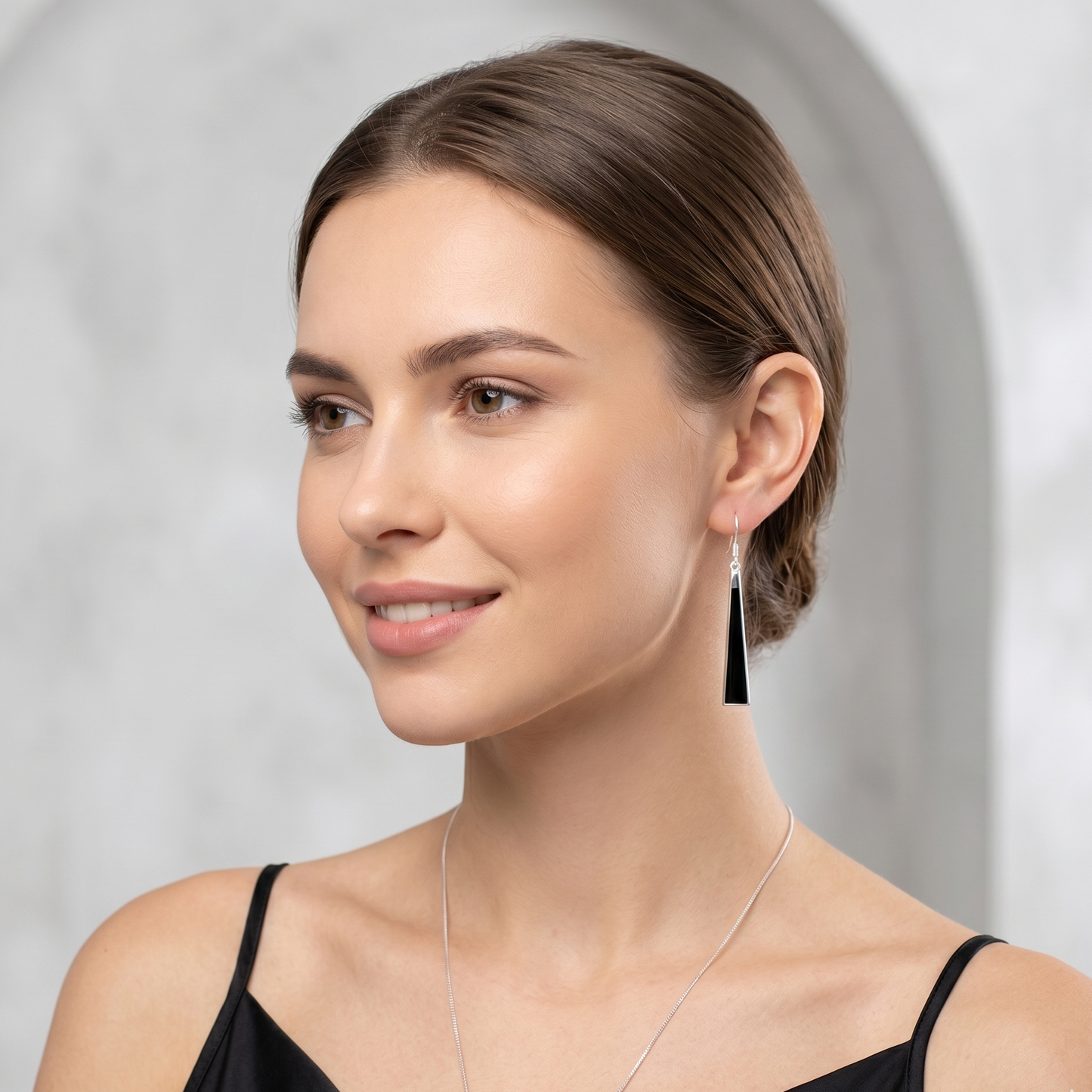Woman wearing a necklace and earrings against a neutral background