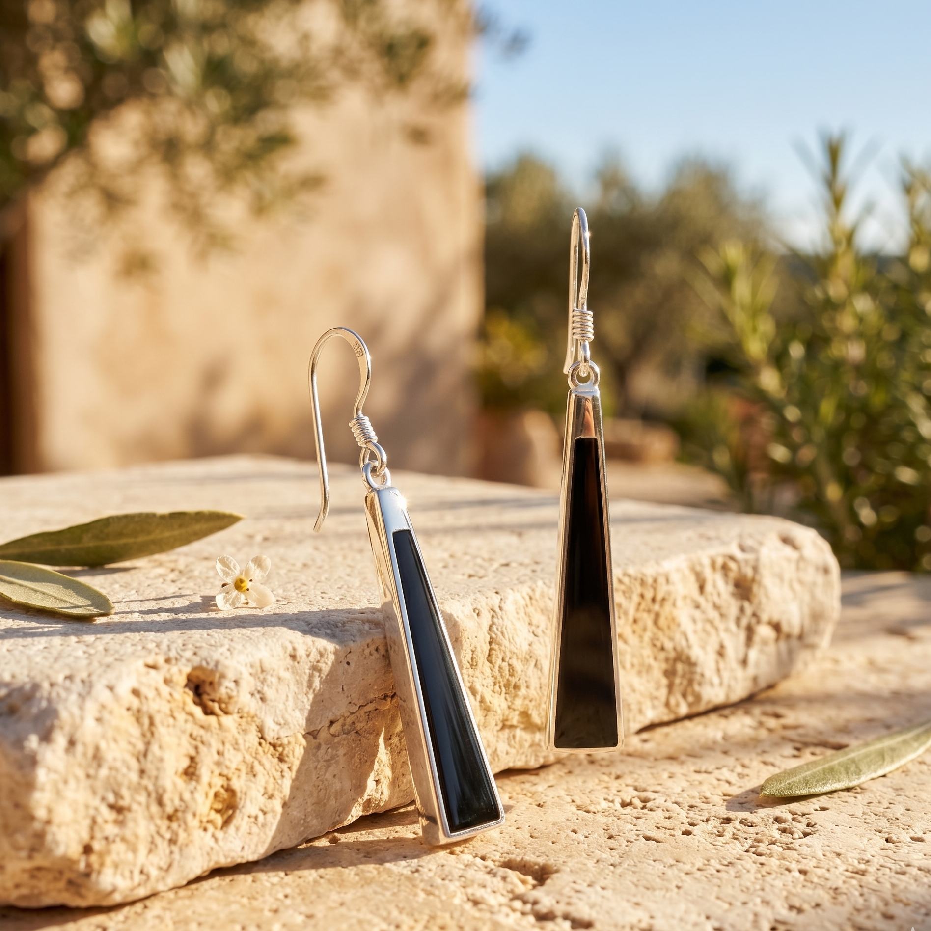 Pair of black and silver earrings on a stone surface with a natural background