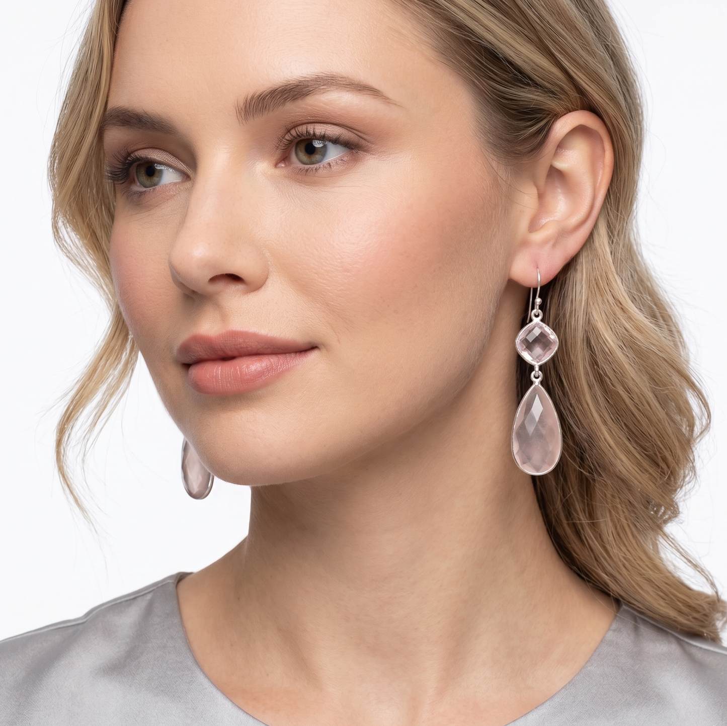 Woman wearing pink teardrop earrings on a white background