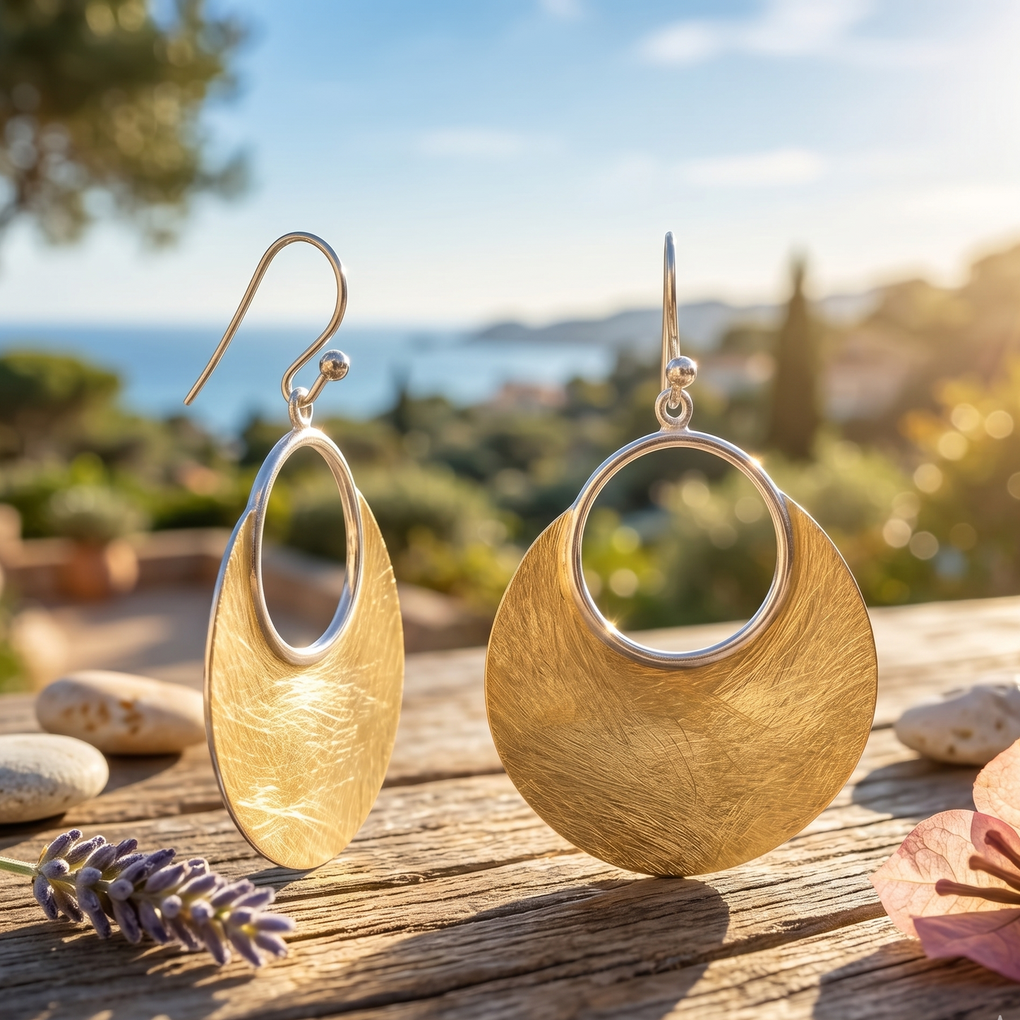 Gold earrings on a wooden surface with a scenic background