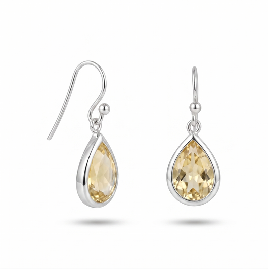 Teardrop-shaped earrings with yellow gemstones on a white background