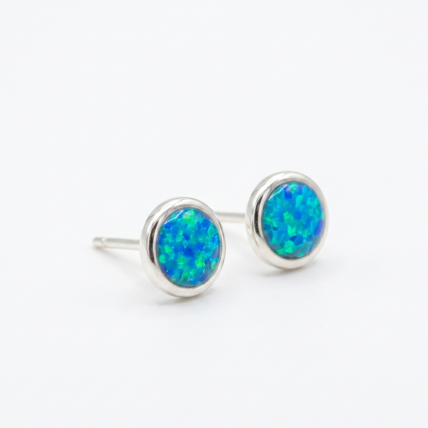 Pair of silver earrings with blue opal stones on a white background
