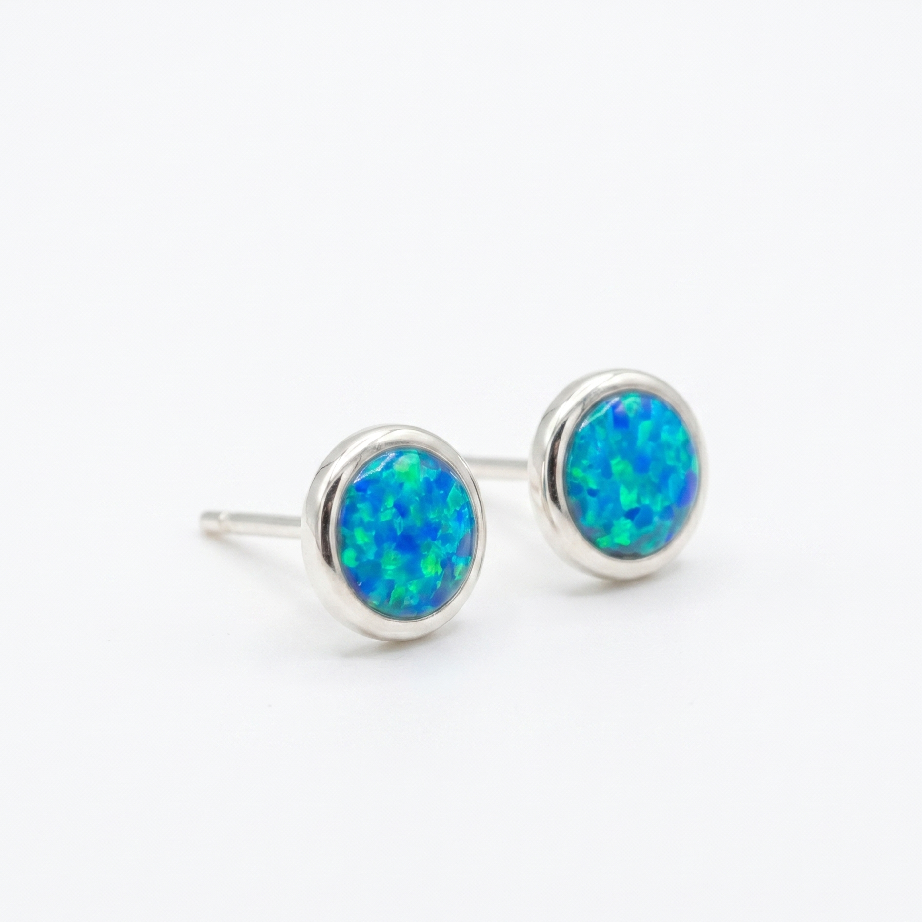 Pair of silver earrings with blue opal stones on a white background