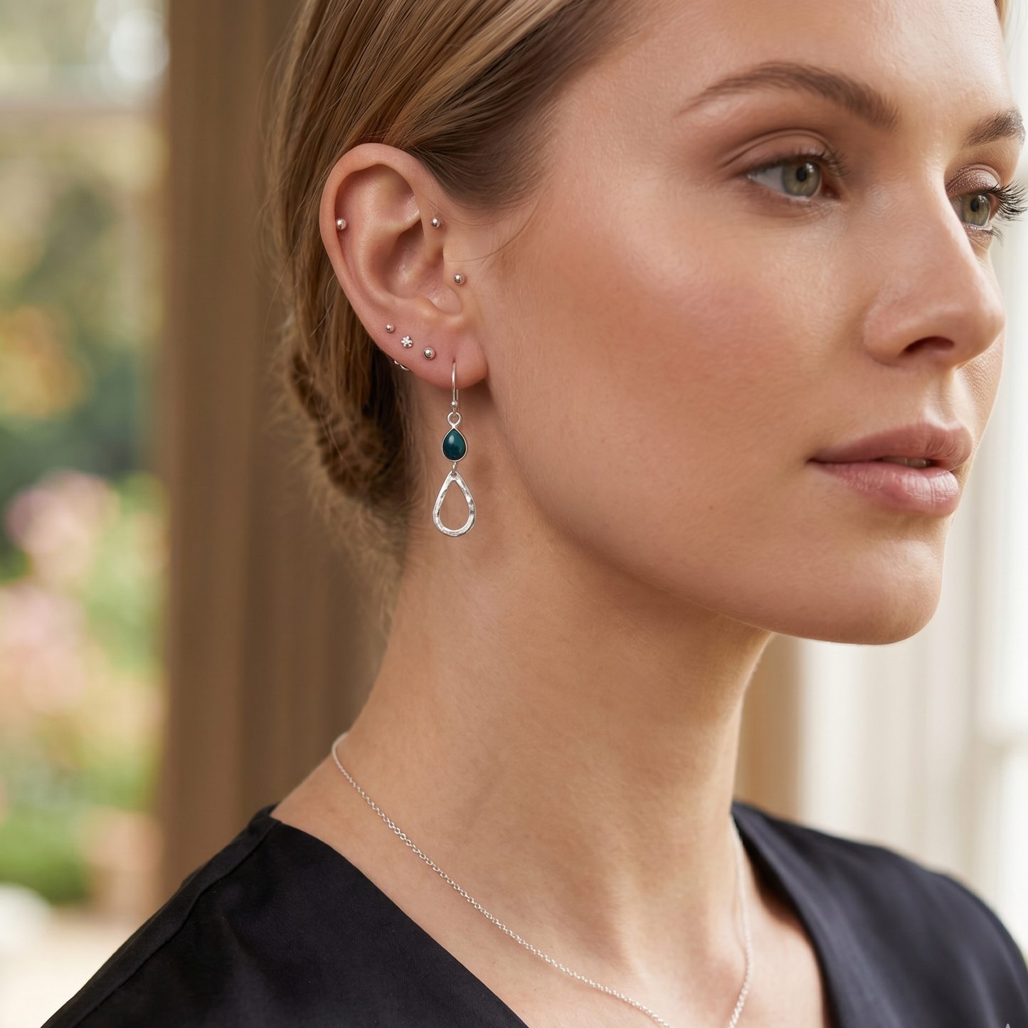 Woman wearing earrings and a necklace with a blurred outdoor background