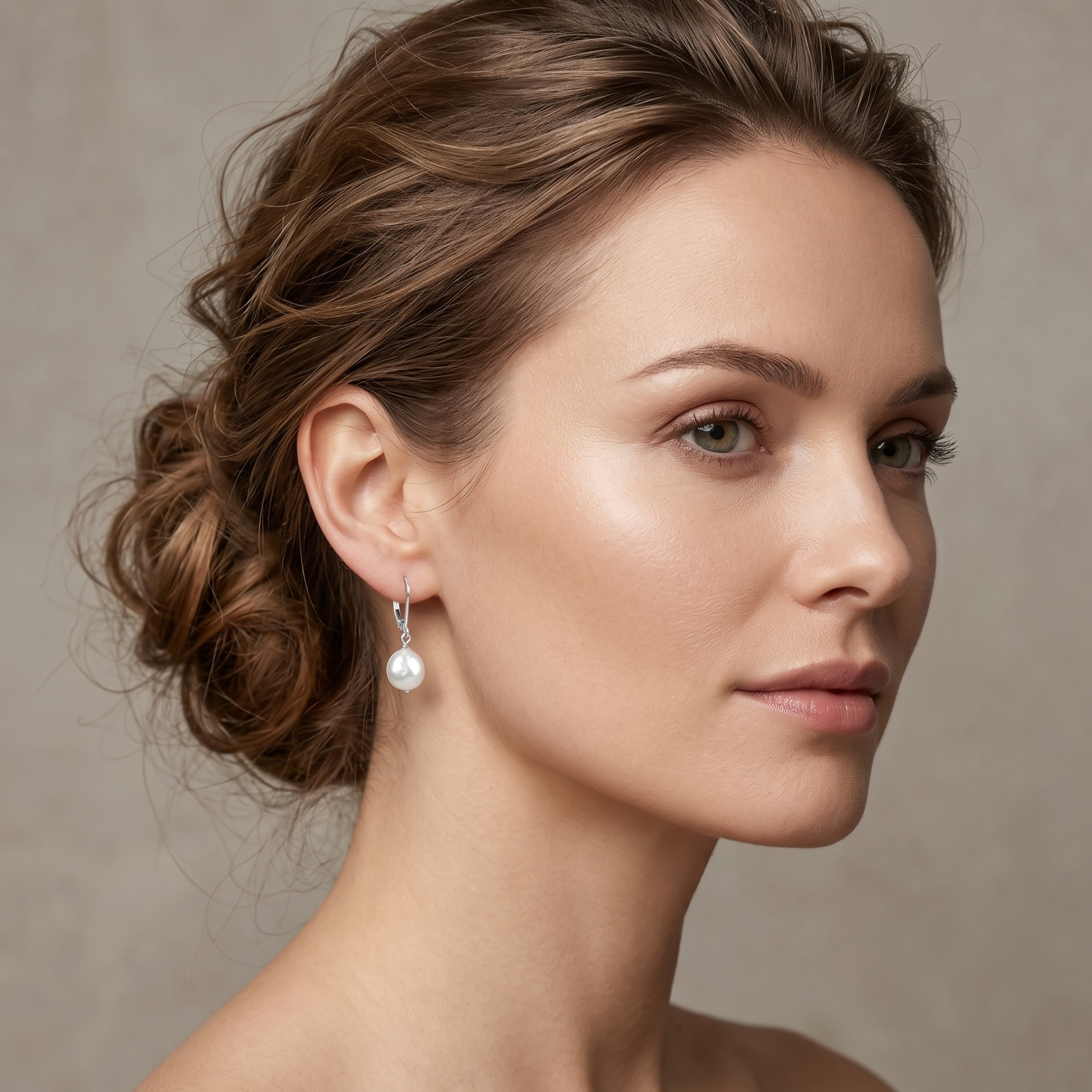 Woman wearing pearl earrings against a neutral background