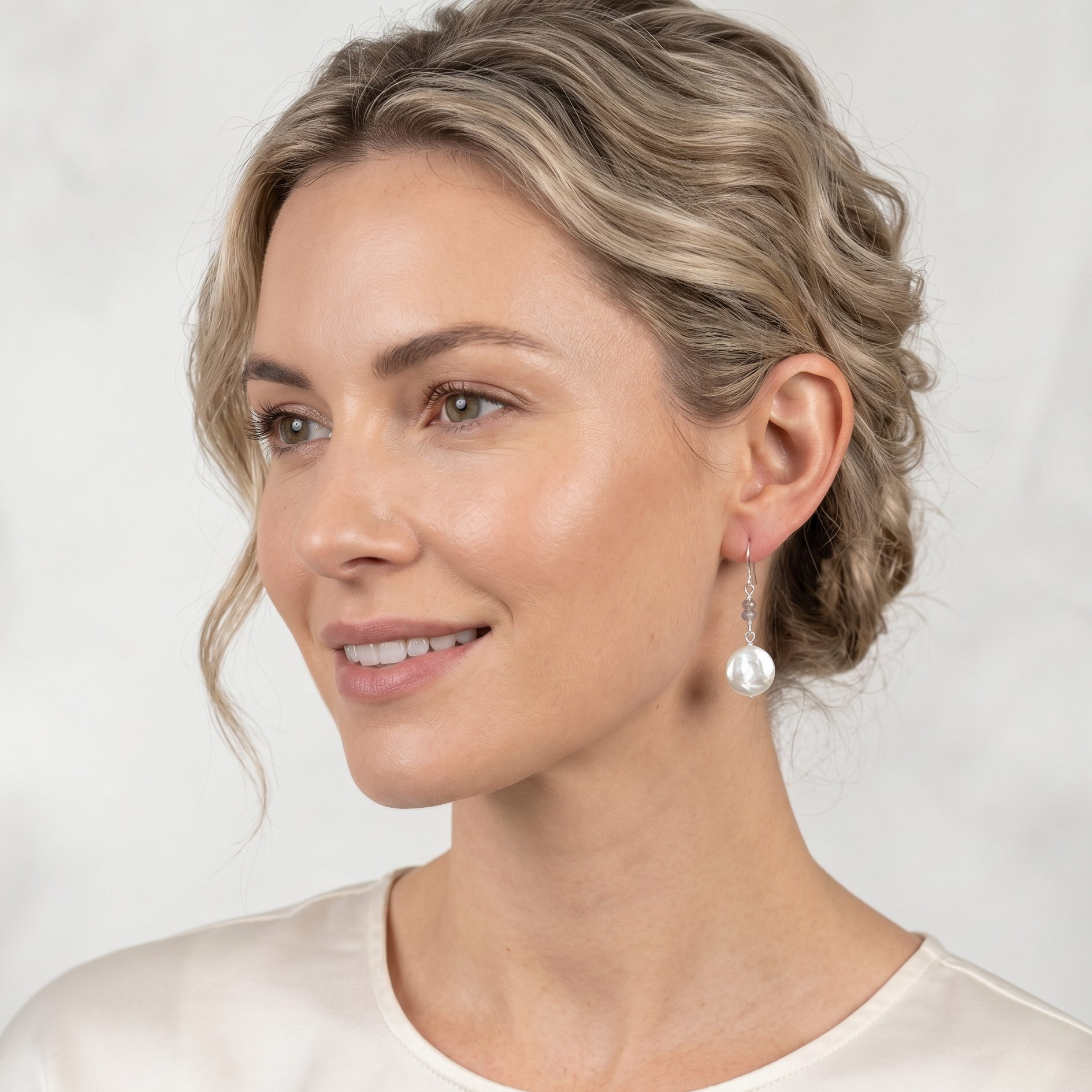 Woman wearing pearl earrings against a plain background