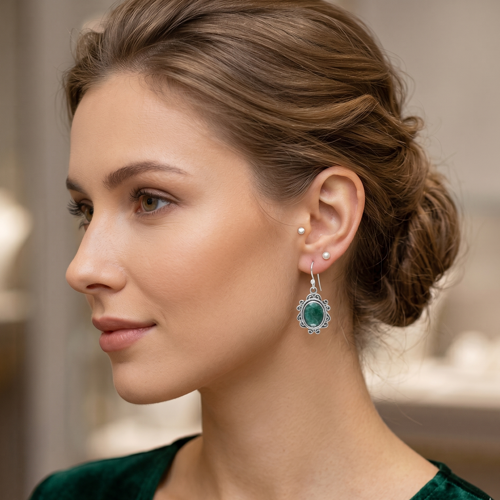 Woman wearing emerald green earrings with a blurred background
