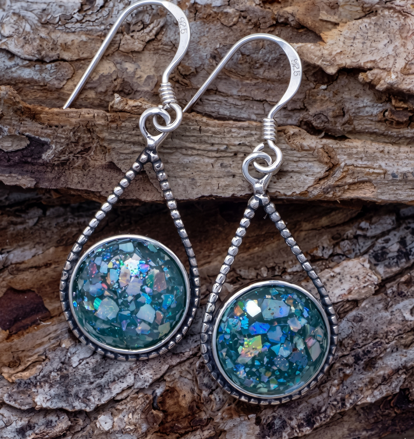 Silver earrings with blue and green speckled stones on a wooden surface