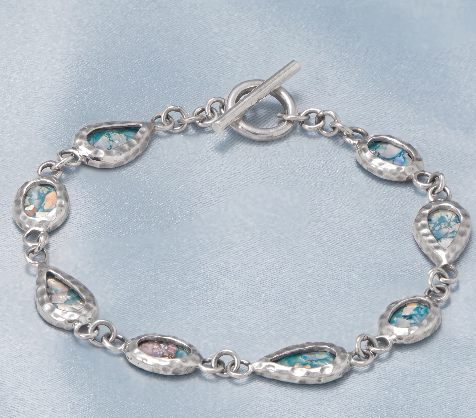 Silver bracelet with teardrop-shaped gemstones on a light blue background