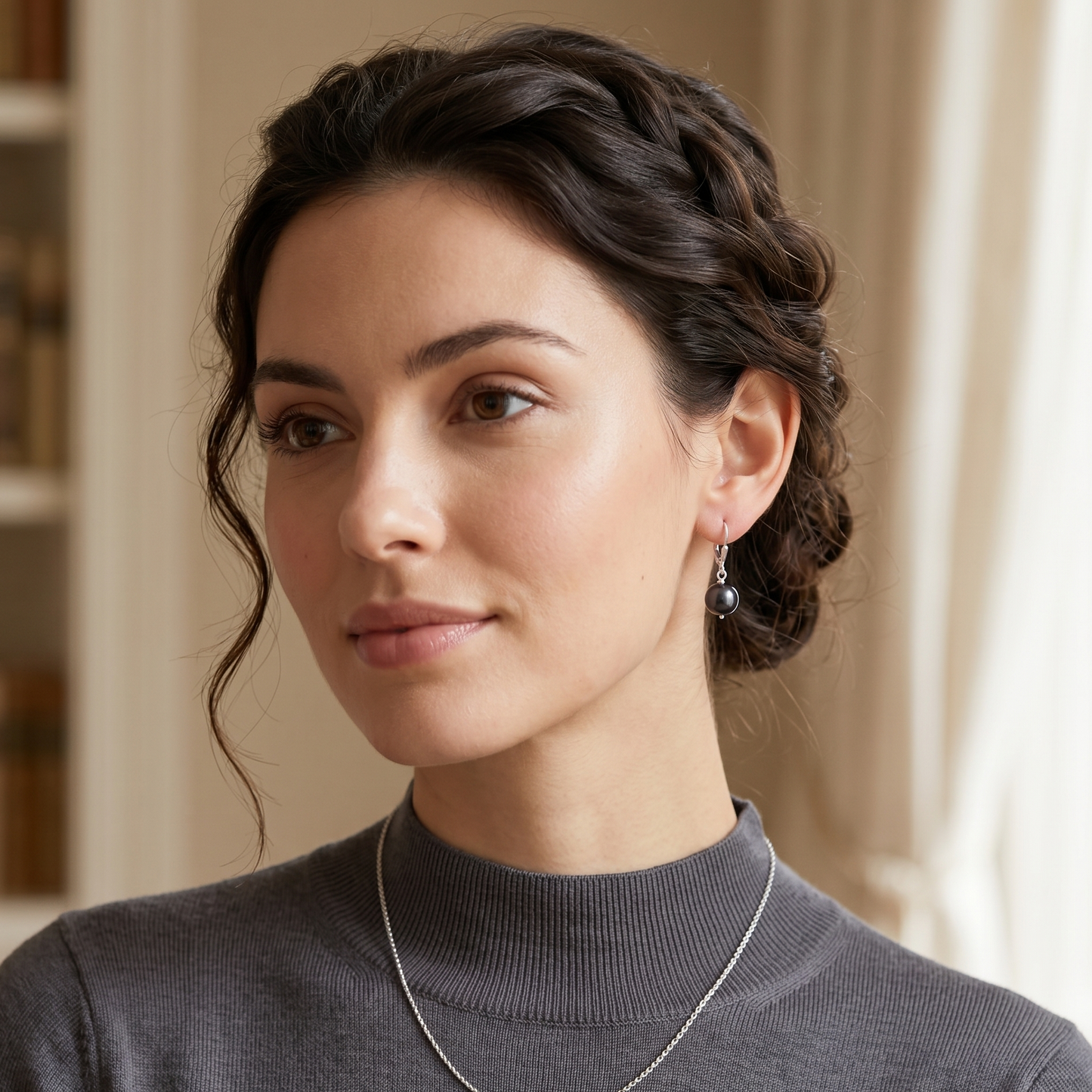Woman wearing a gray turtleneck sweater with a blurred indoor background