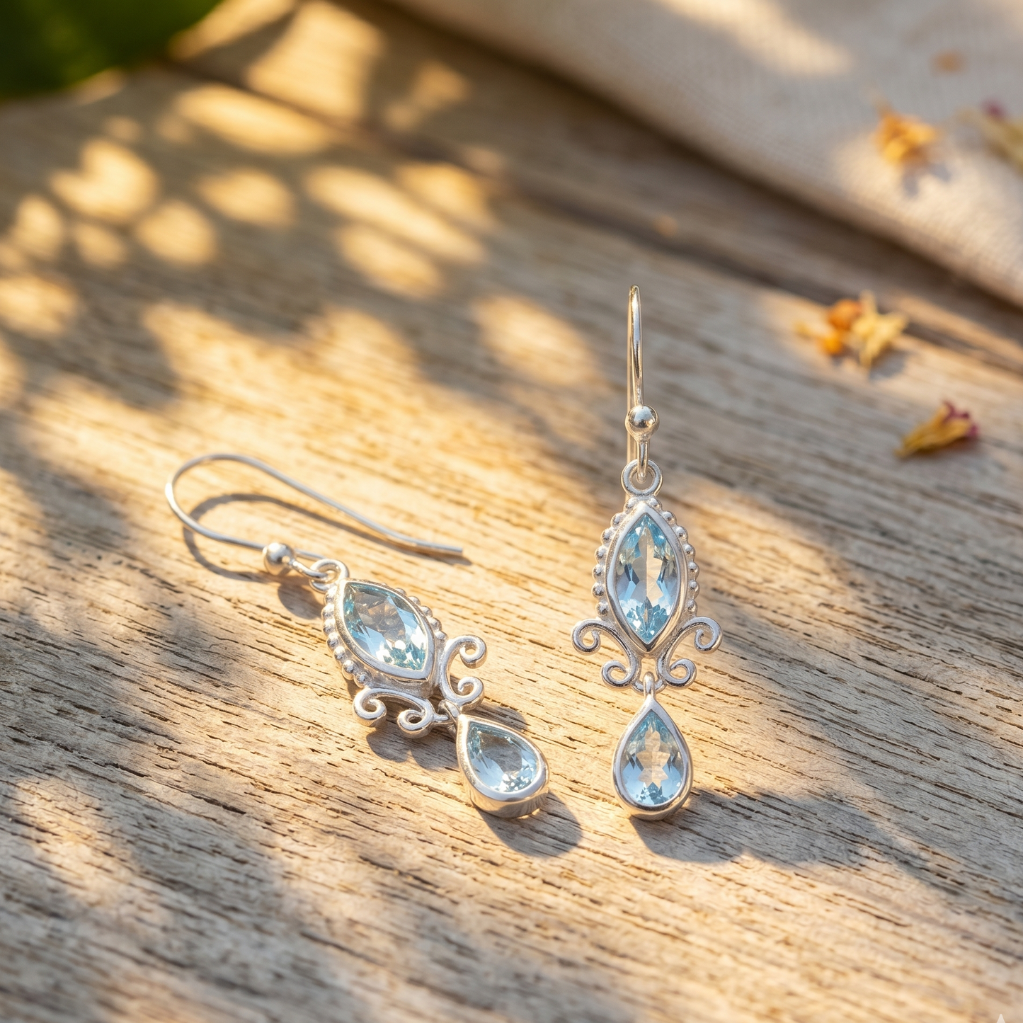 Pair of silver earrings with teardrop-shaped gemstones on a wooden surface.