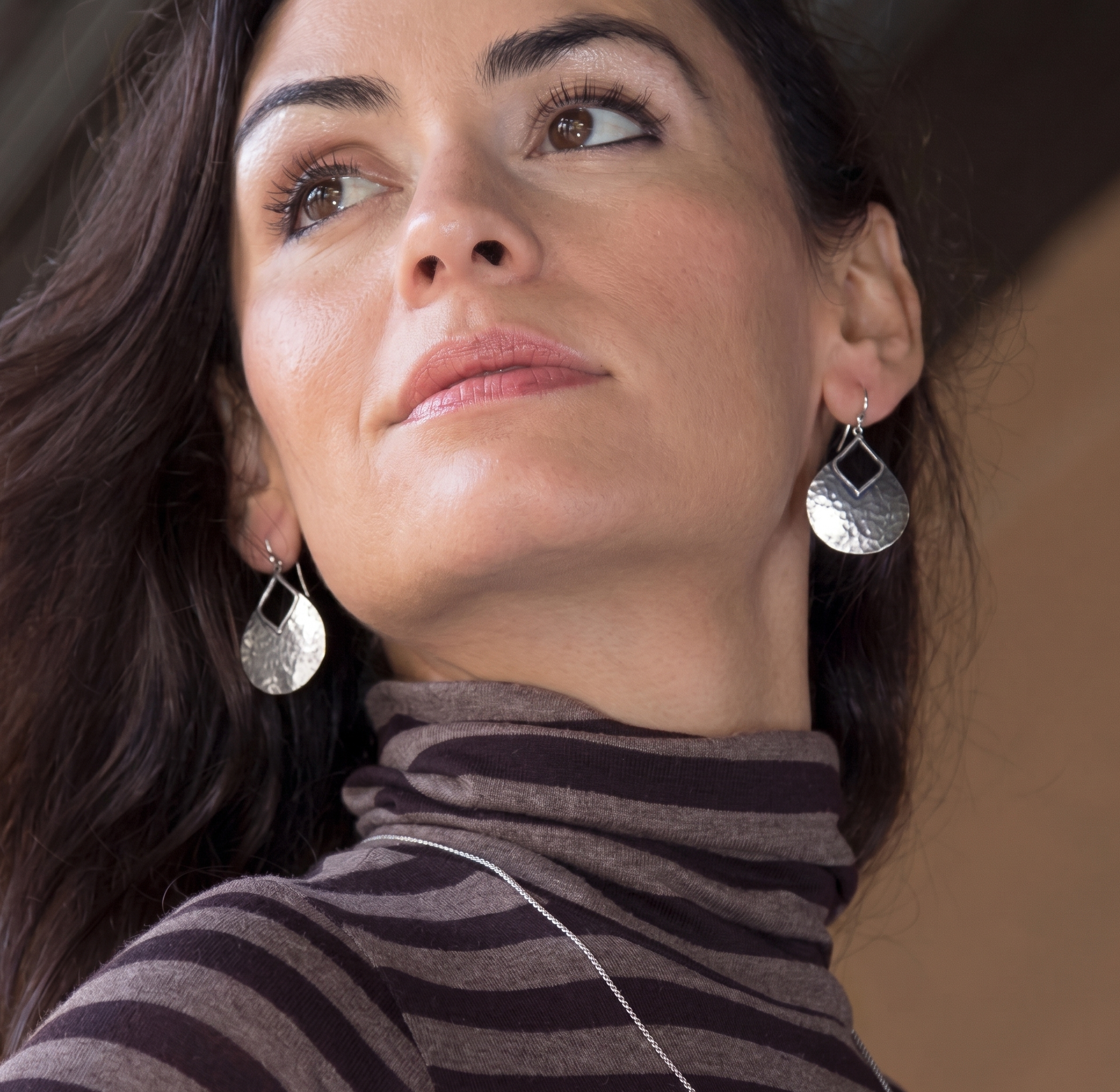 Woman wearing silver earrings with a neutral background