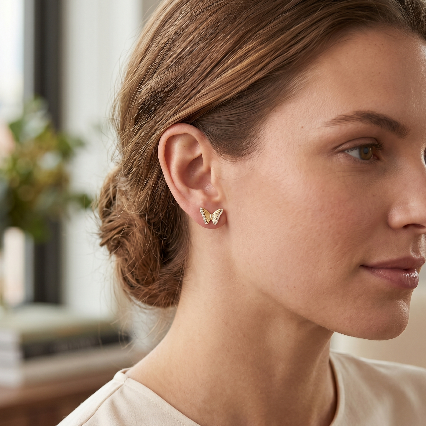 Woman wearing butterfly earrings with a blurred indoor background