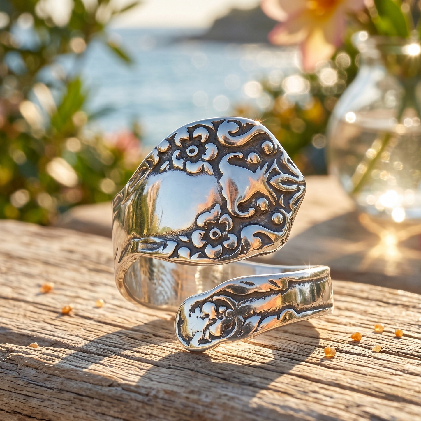 Silver ring with intricate designs on a wooden surface with a blurred natural background