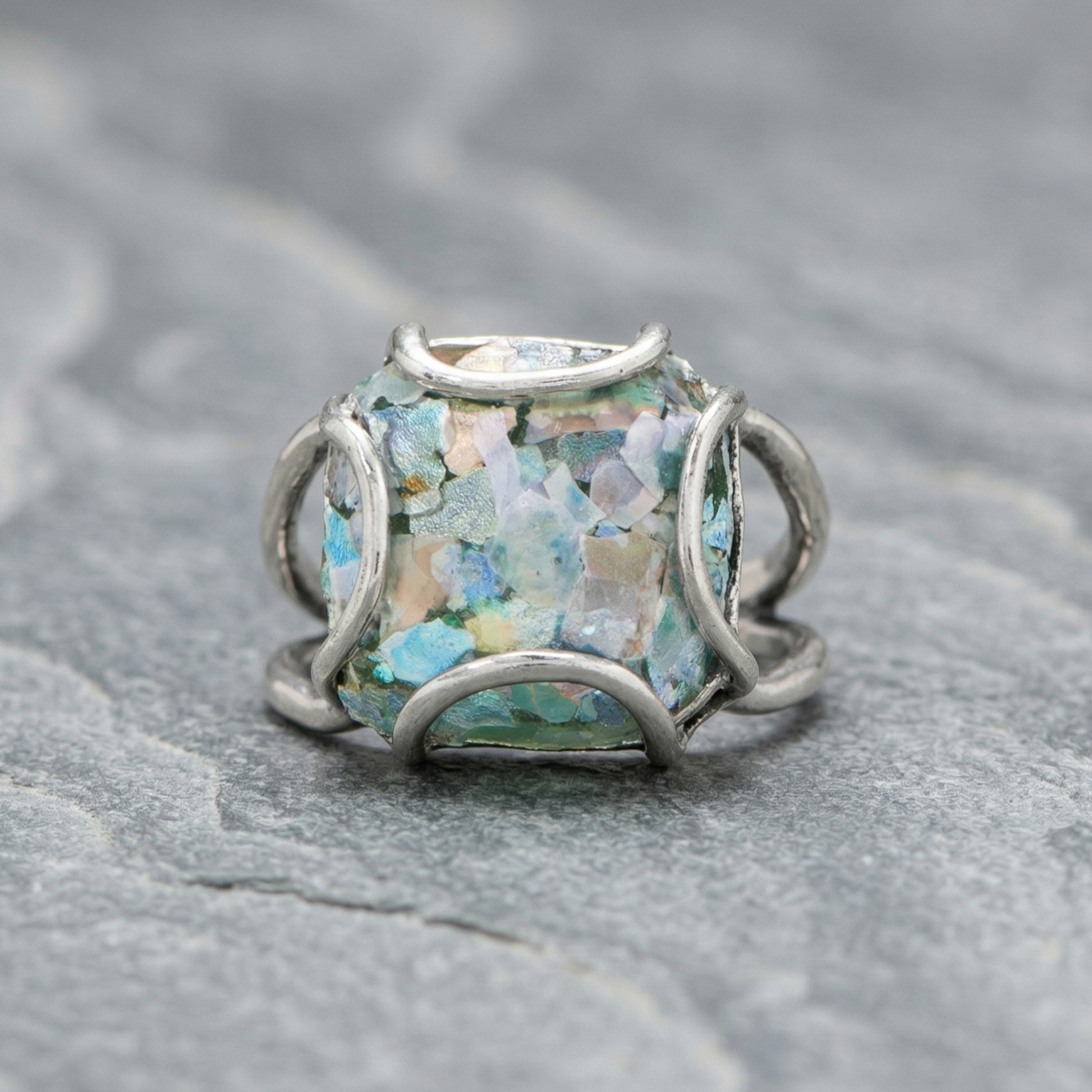 Silver ring with a colorful gemstone on a textured gray surface