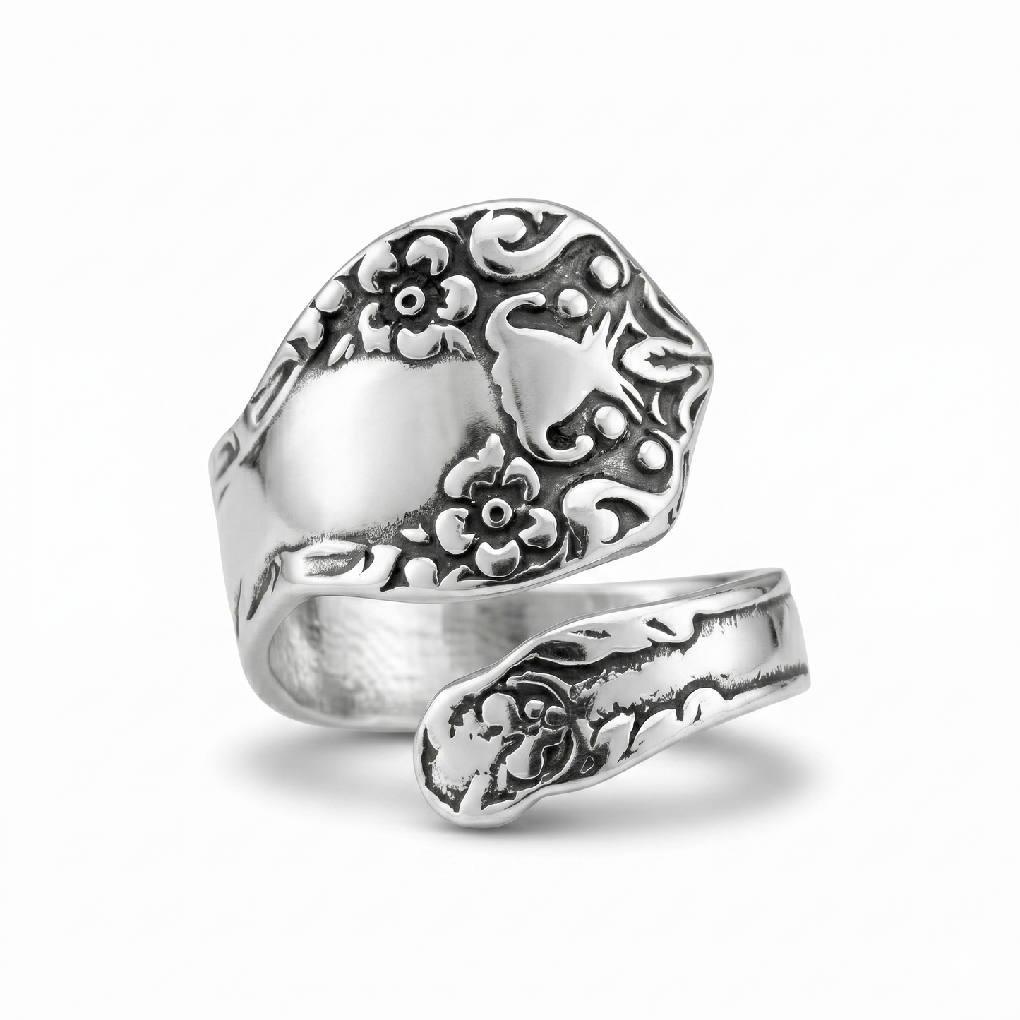 Silver ring with intricate floral designs on a white background