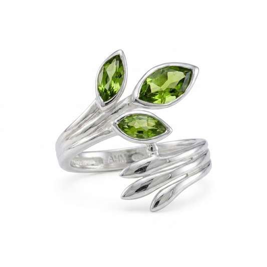 Silver ring with green gemstones on a white background
