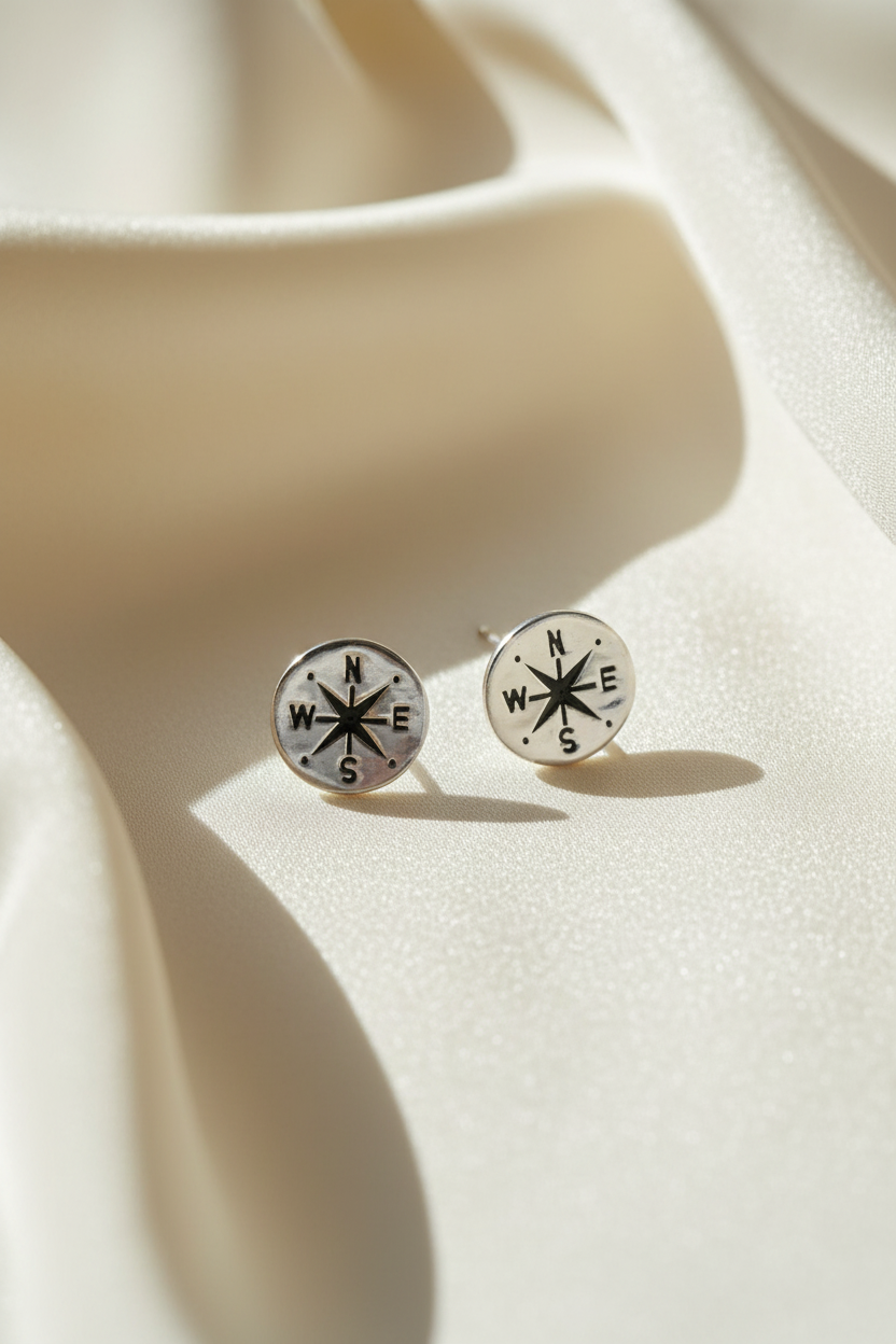 Compass stud earrings on cream silk fabric